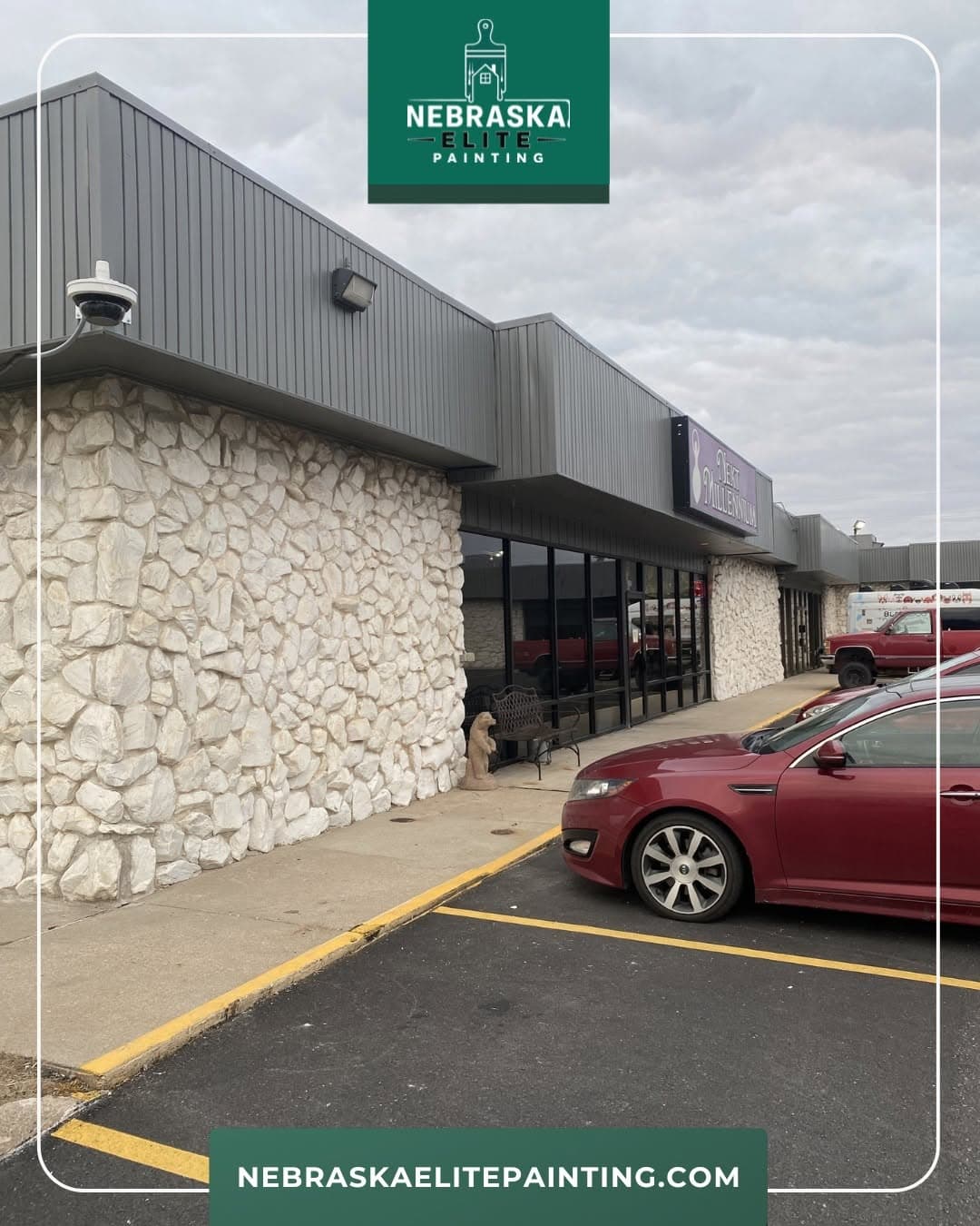 Exterior view of Nebraska Elite Painting building with stone facade and red car parked.