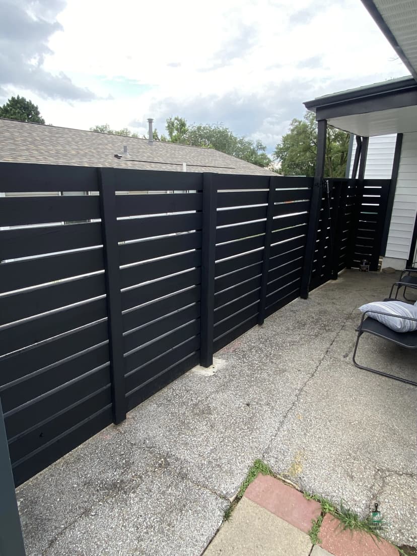 Modern black slatted fence in a residential backyard, providing privacy and style.