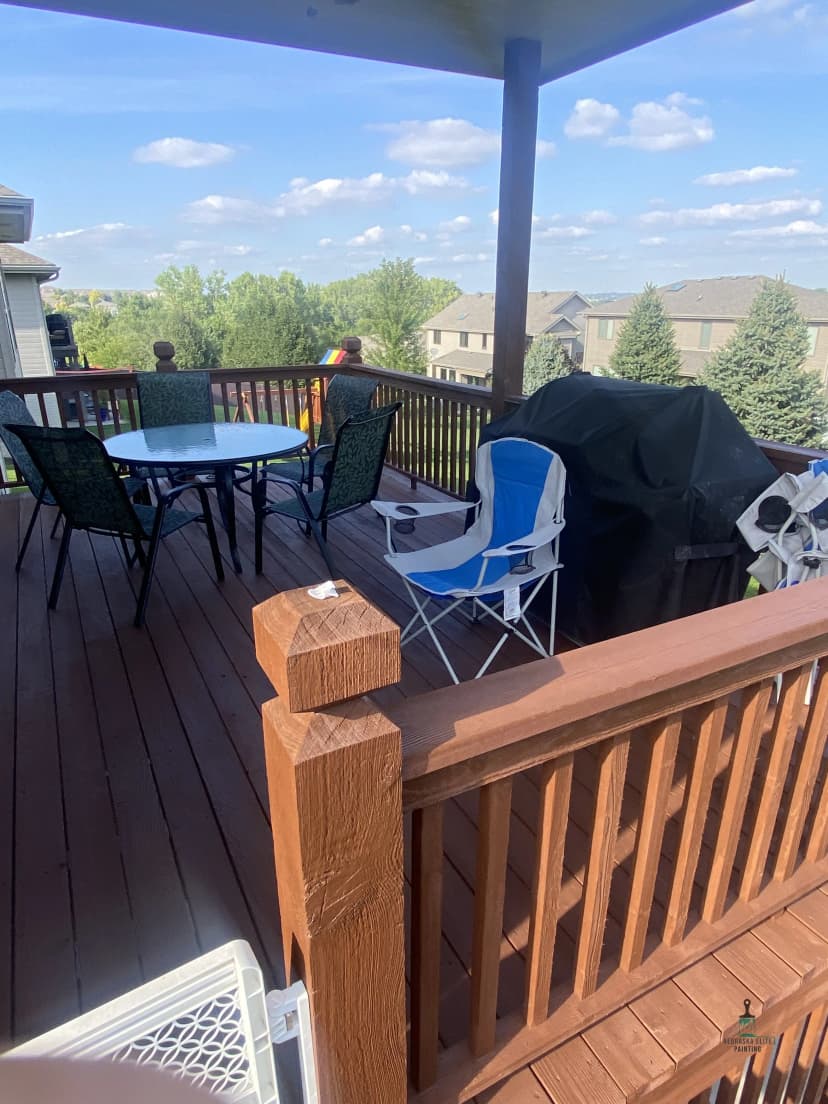 Sunny outdoor patio with furniture, grill, and scenic view of houses and trees.