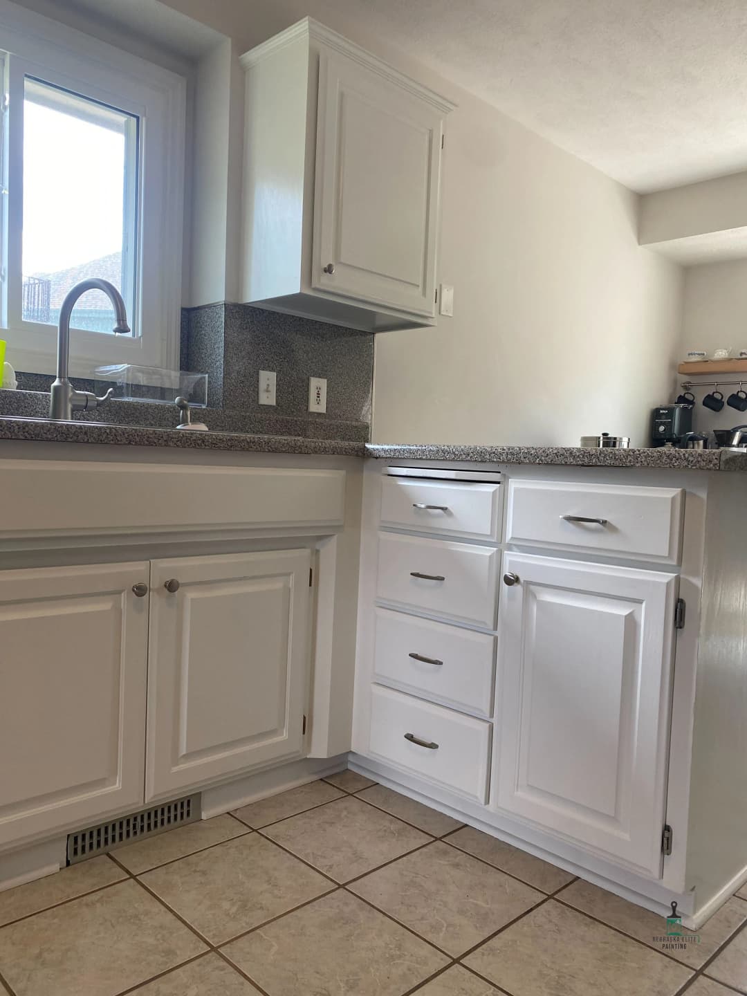 Modern kitchen with white cabinetry, granite countertops, and a stainless steel sink.