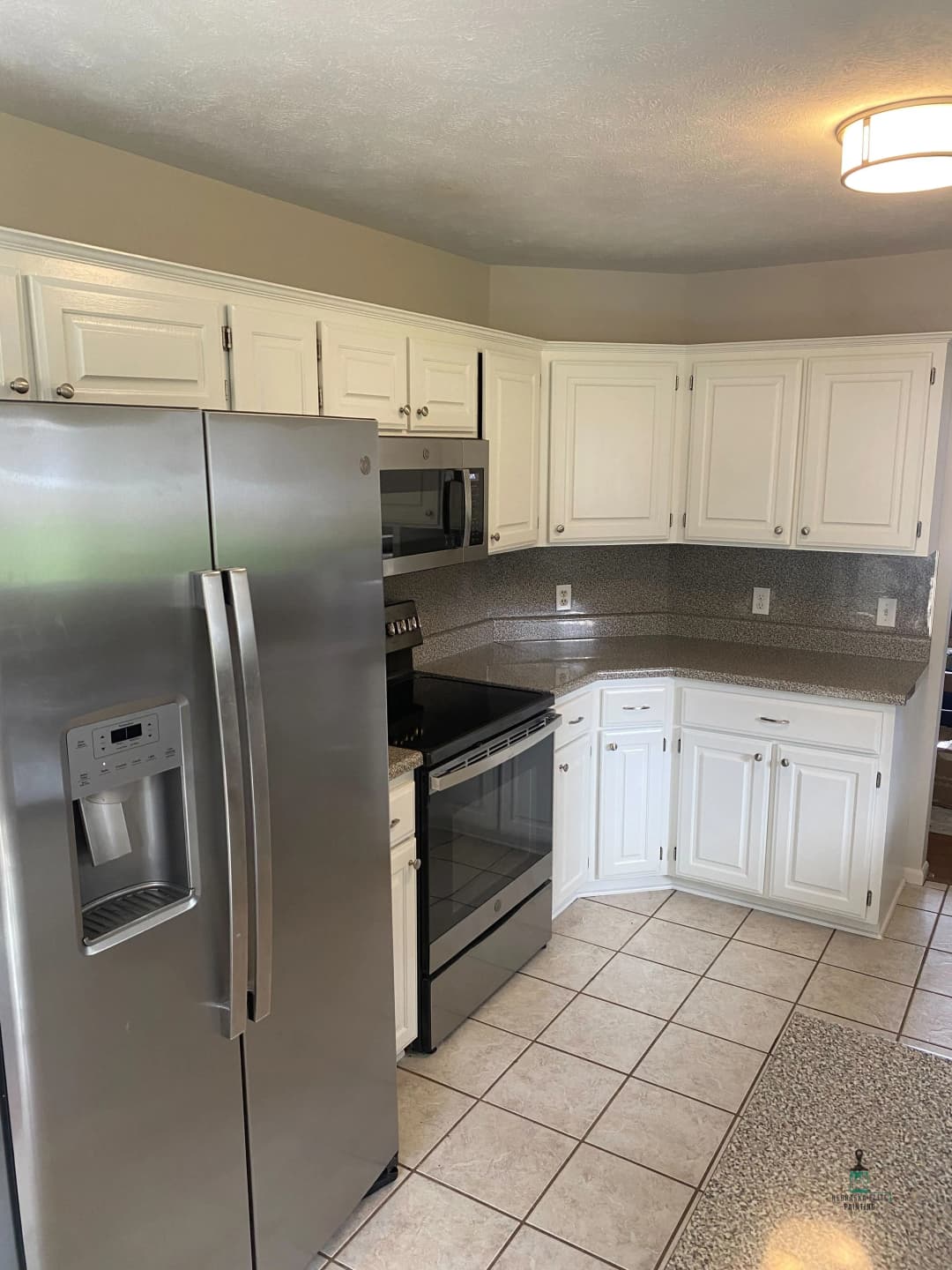 Modern kitchen with stainless steel appliances, white cabinets, and tiled flooring.