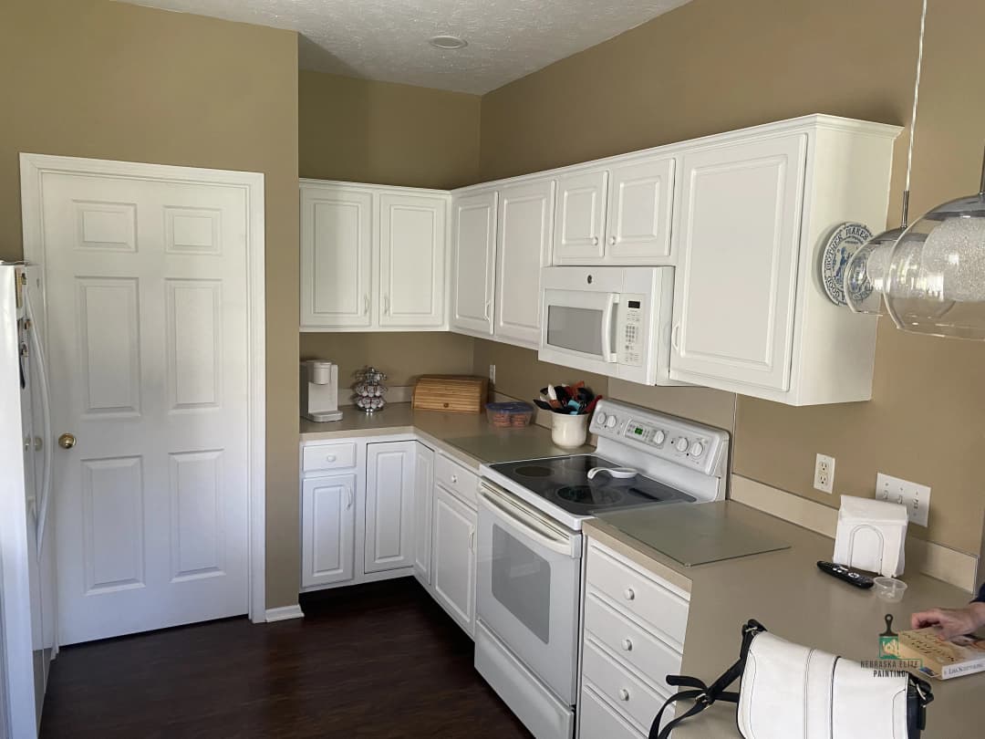 Bright modern kitchen with white cabinets, stainless steel appliances, and wooden accents.
