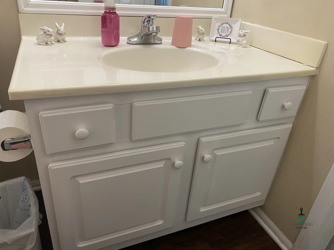 White bathroom vanity with sink, mirror, and decorative ceramic bunnies.