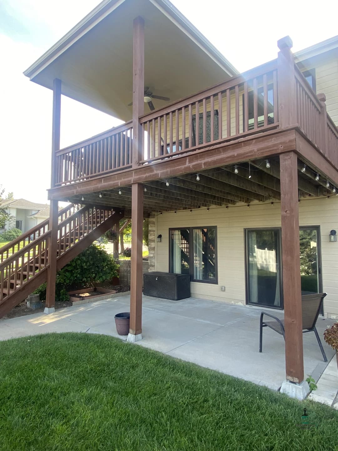 Two-story house featuring a wooden deck, outdoor seating, and landscaped lawn.