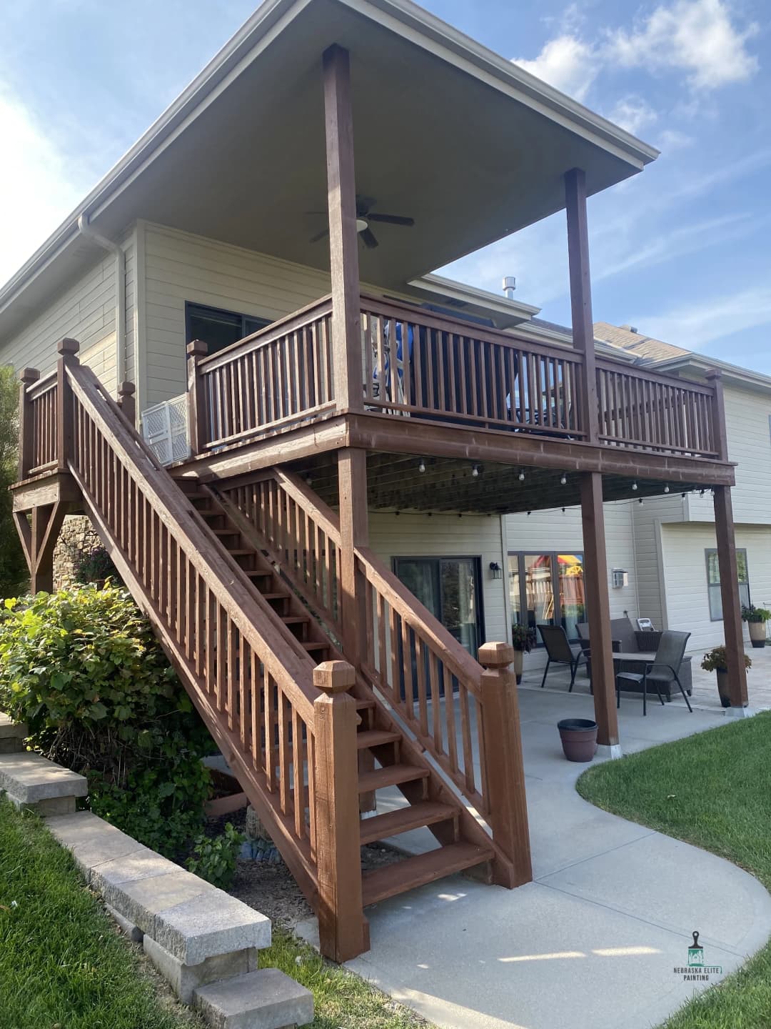 Elevated wooden deck with stairs and outdoor seating in a residential backyard setting.