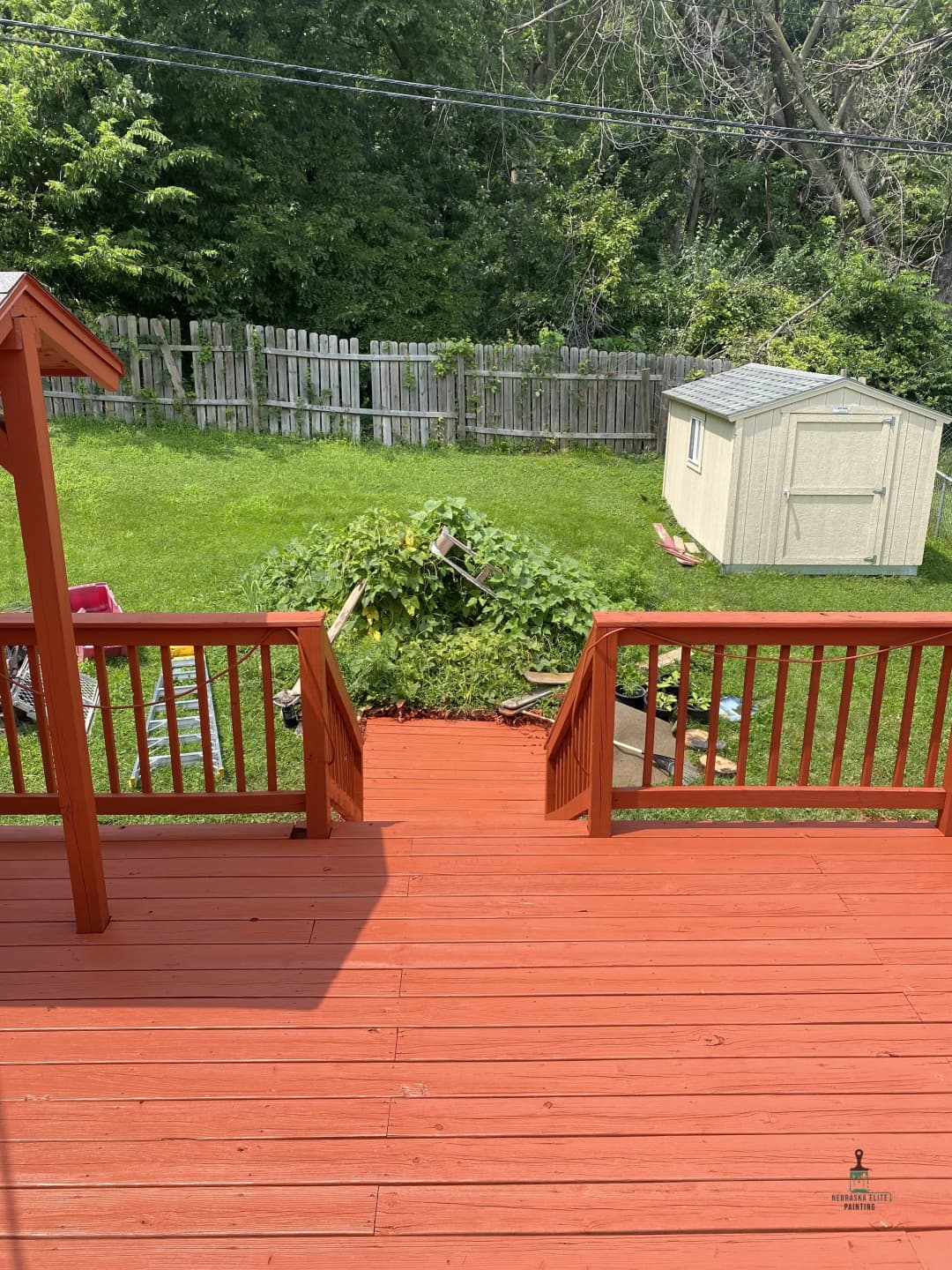 View from a wooden deck overlooking a backyard with a shed and green garden area.