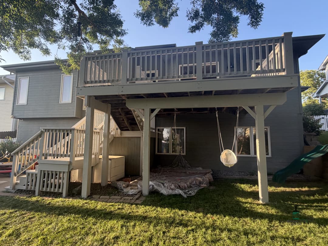 Backyard view of a house with a second-floor deck and swing set underneath.
