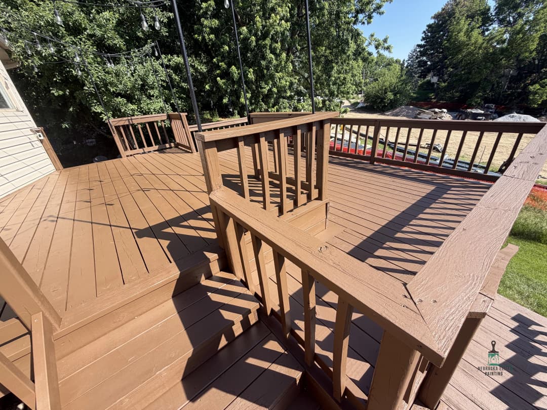 Spacious wooden deck with railing, surrounded by greenery and outdoor features.