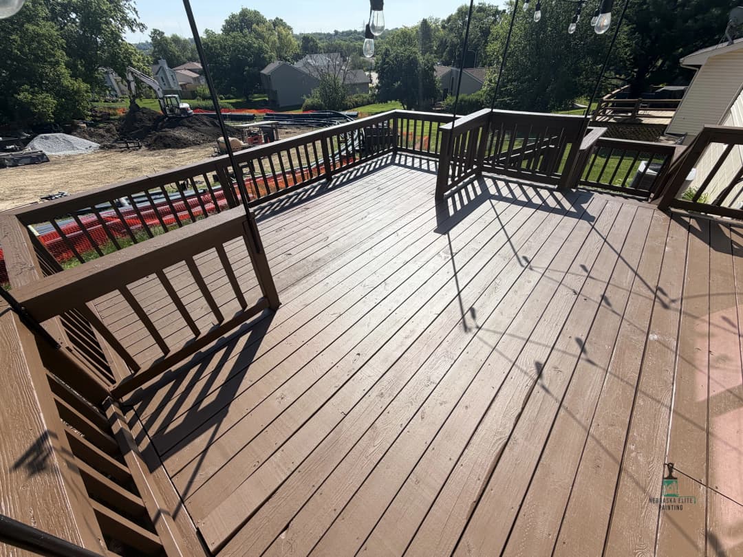 Spacious wooden deck with railing, showcasing outdoor living space and surrounding greenery.