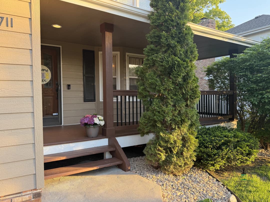 Charming porch with potted flowers and a wooden railing at a residential home entrance.