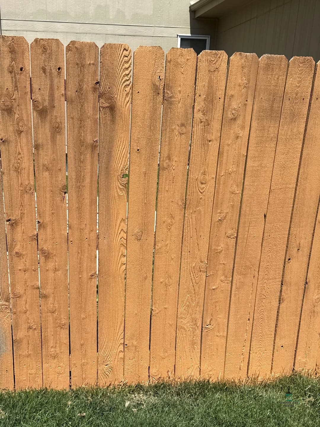 Wooden fence with uneven planks, showcasing a natural finish and grassy yard behind it.