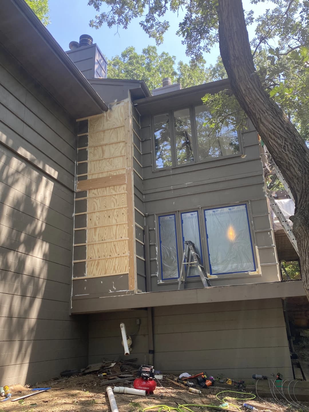 Home exterior renovation with scaffolding, new windows, and wood paneling preparation.