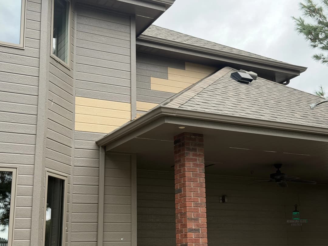 Home exterior showing new siding installation and a brick column under a covered porch.