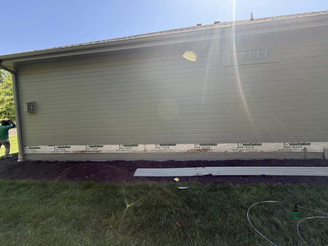 Newly sided home exterior featuring green siding and landscaping preparation.