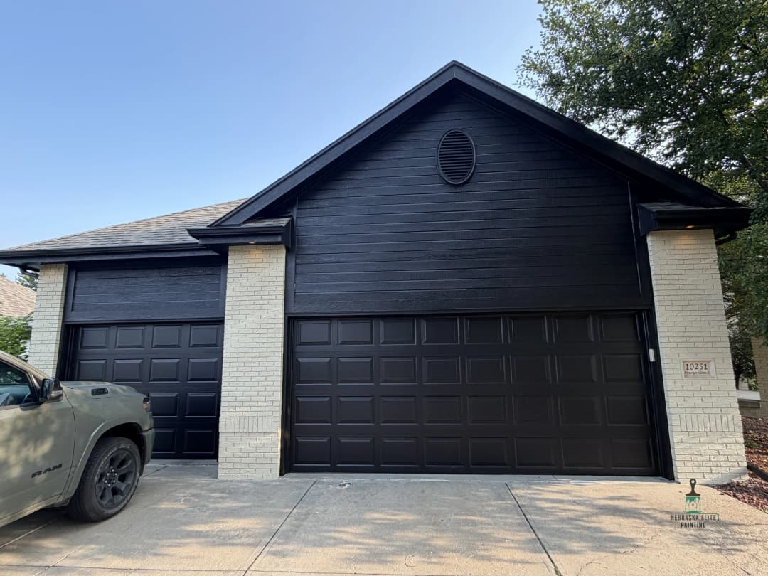 Modern black garage doors on a stylish home with light brick accents and a clean driveway.