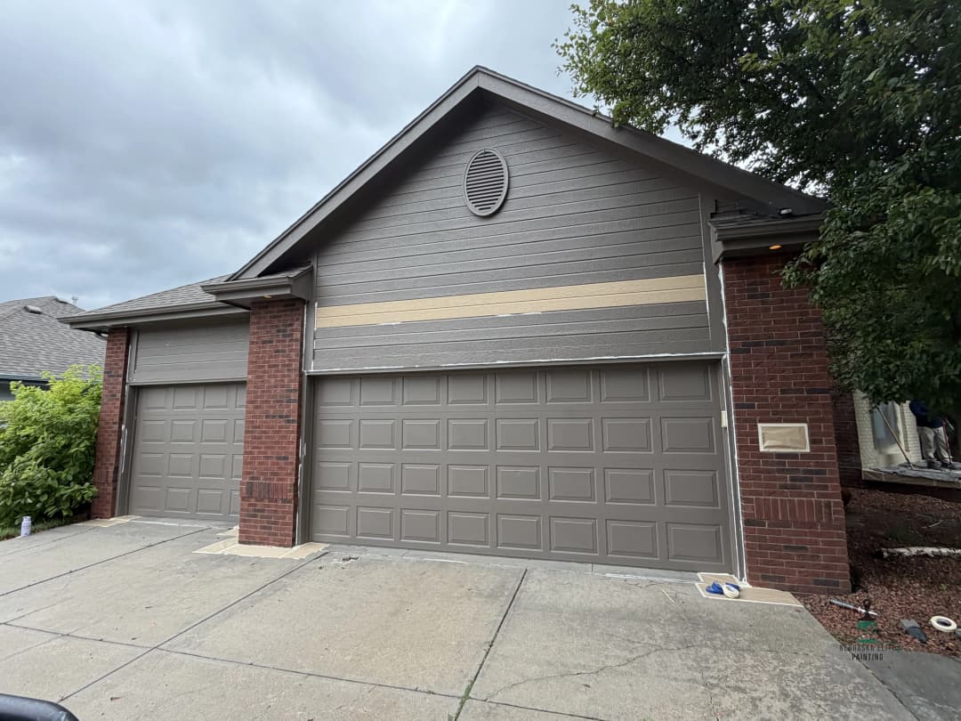 Gray house with brick accents and double garage, under cloudy skies.