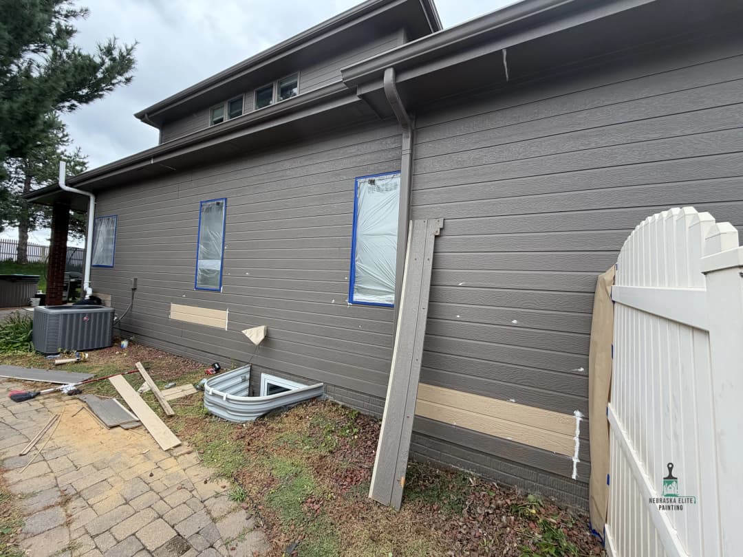 Home exterior undergoing renovation with siding, window frames, and tools visible.