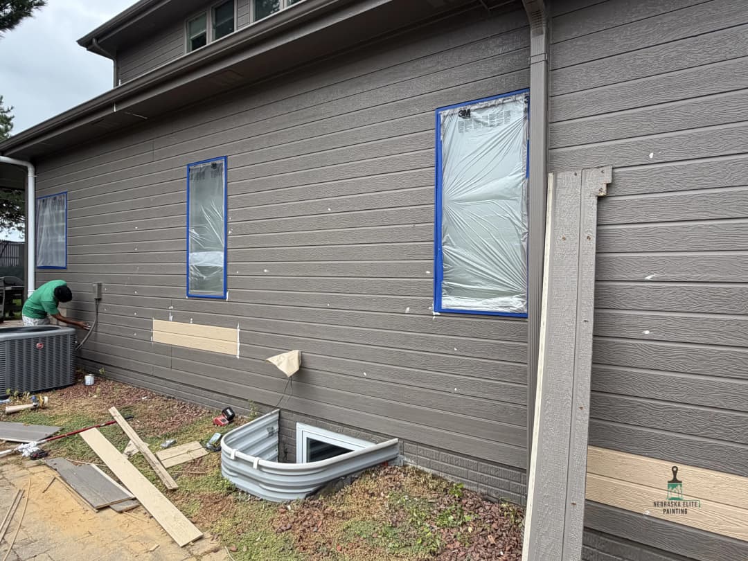 Home exterior renovation with window coverings and construction materials visible.
