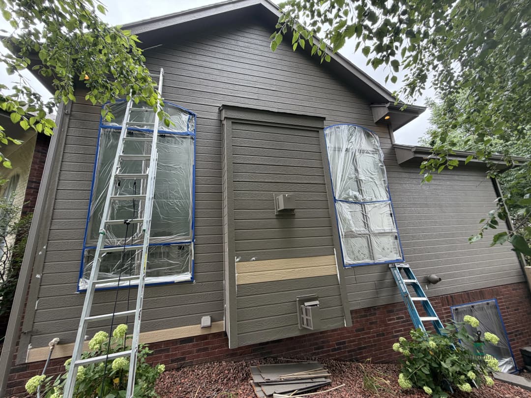 House exterior with painted siding, ladders, and covered windows for renovation.
