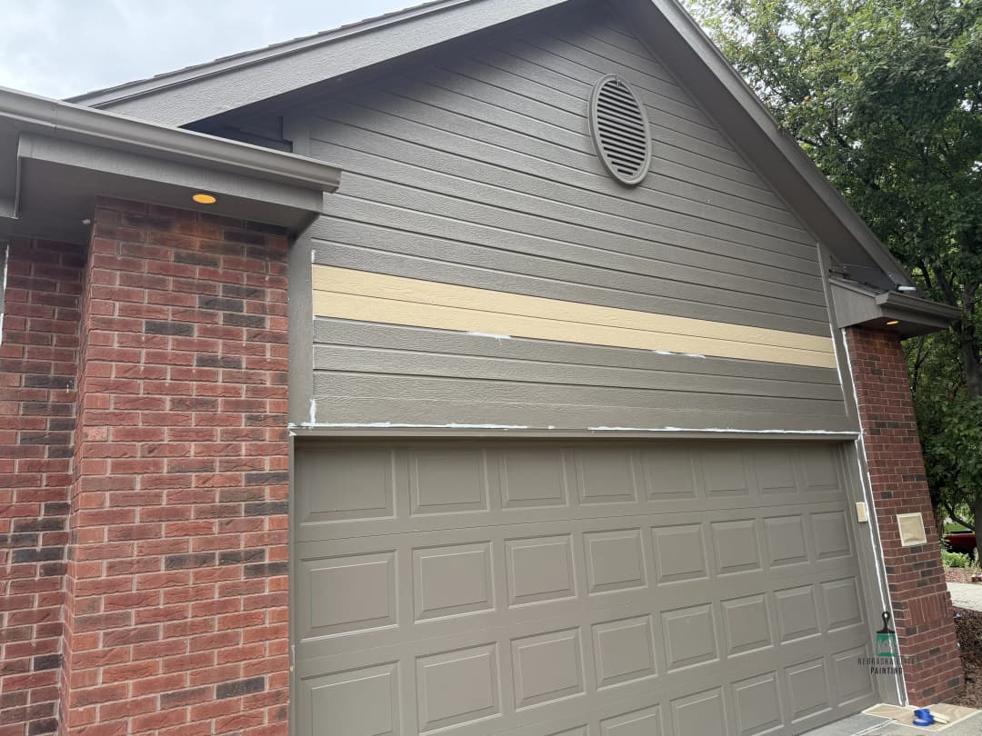 Newly painted garage door and siding on a residential home with brick accents.