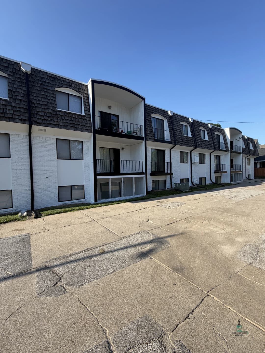 Modern apartment building with balconies and a paved pathway in daylight.