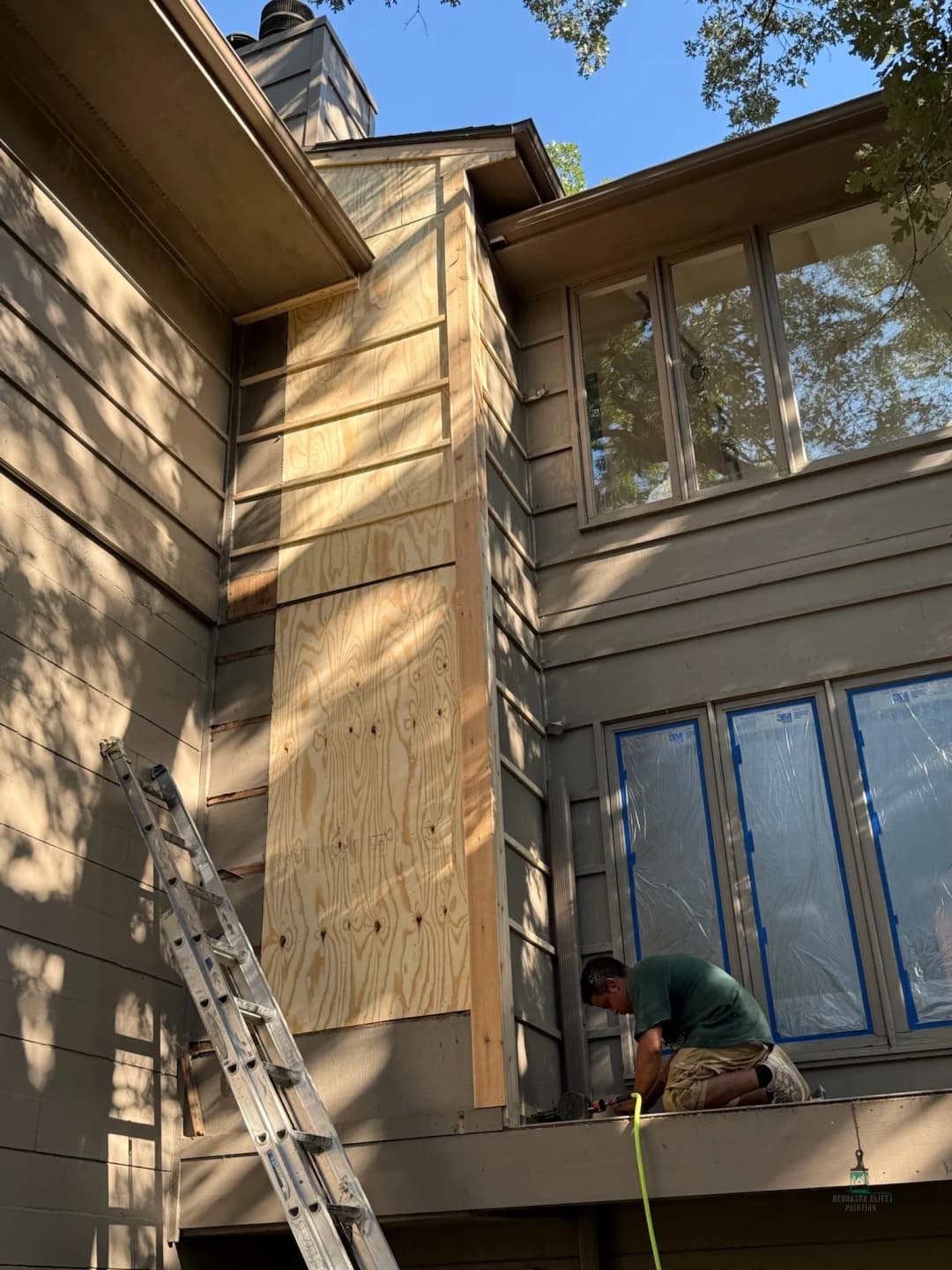 Home renovation with carpenter working on exterior wall cladding installation.