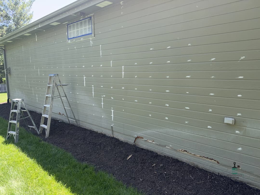 House exterior with fresh paint patches, two ladders, and manicured lawn.