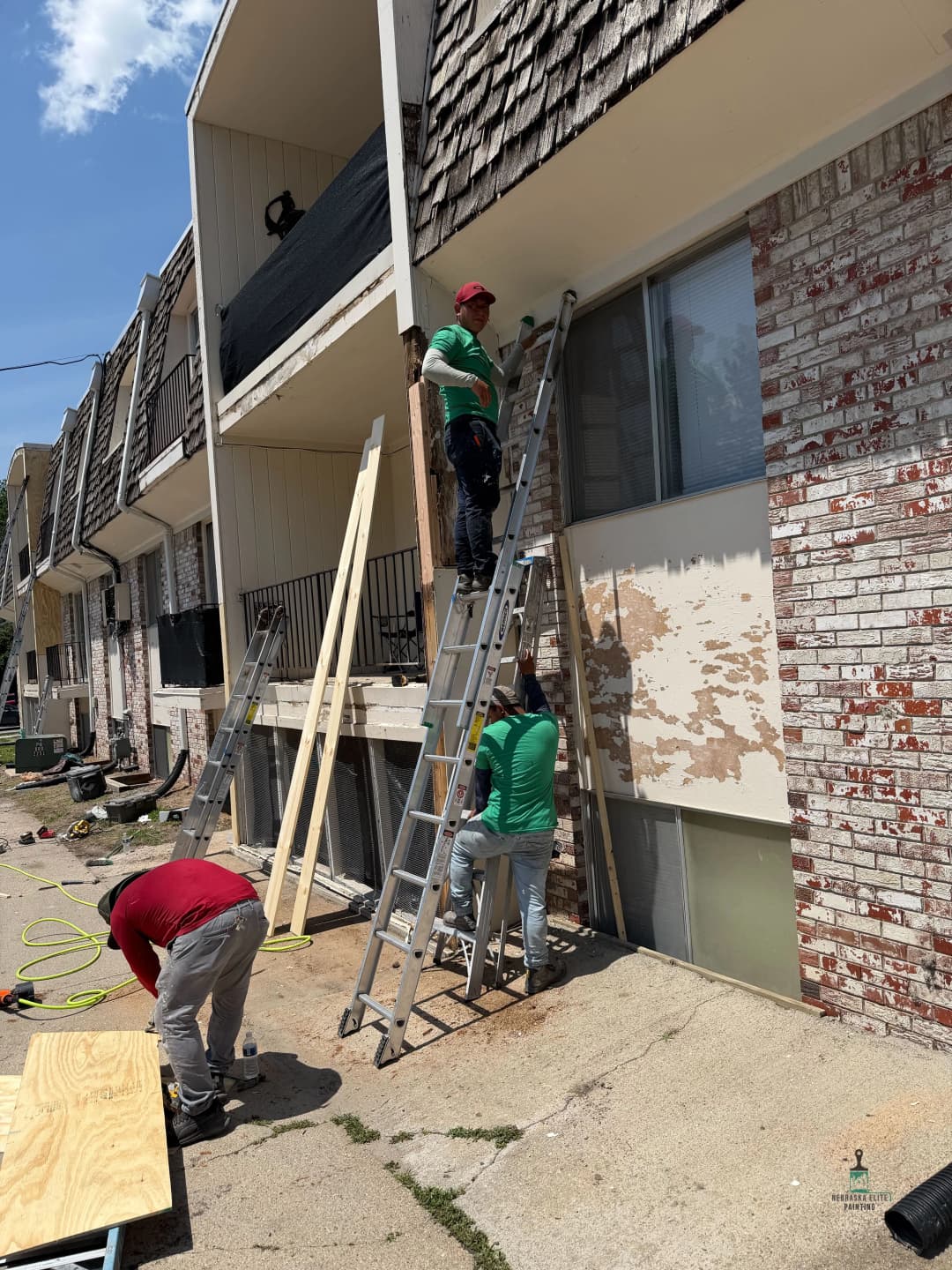 Workers using ladders for exterior renovations on a multi-unit building.