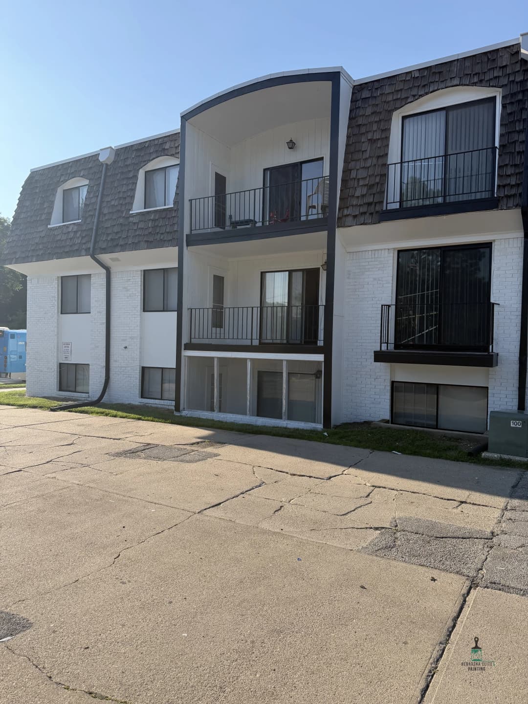Exterior view of a multi-unit apartment building with balconies and a driveway.