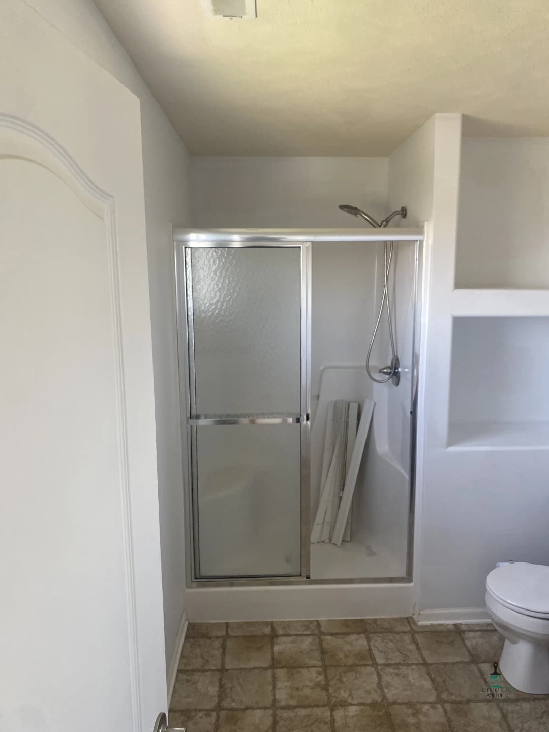 Modern bathroom with a glass shower enclosure and beige tile flooring.