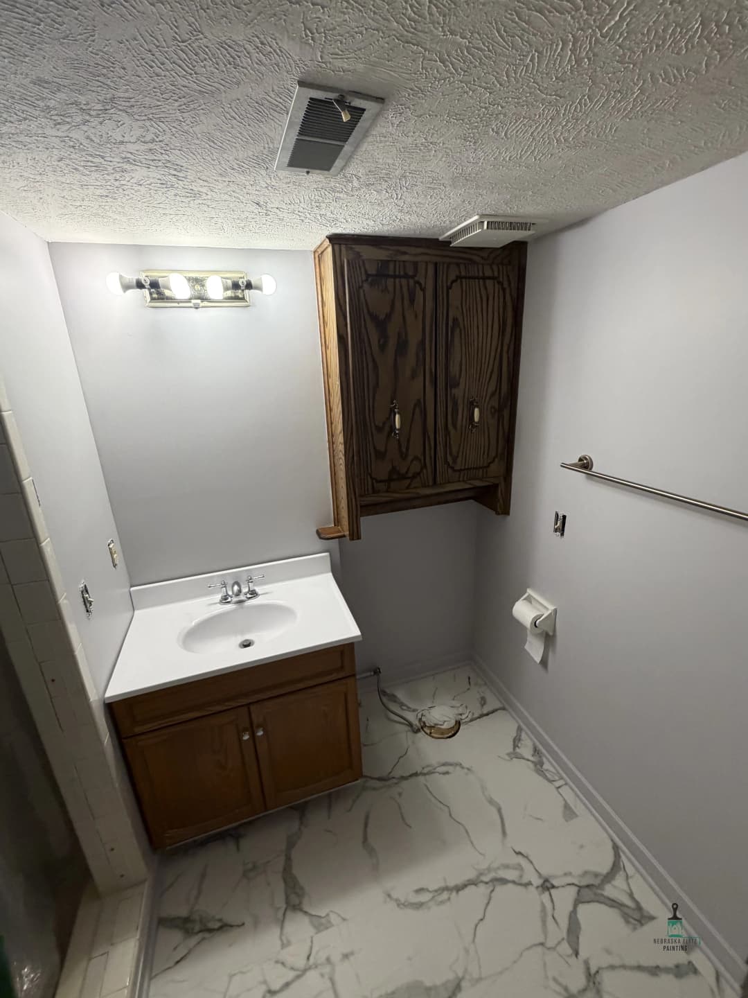 Modern bathroom with vanity, mirror, wooden cabinet, and marble flooring. Natural light source visible.
