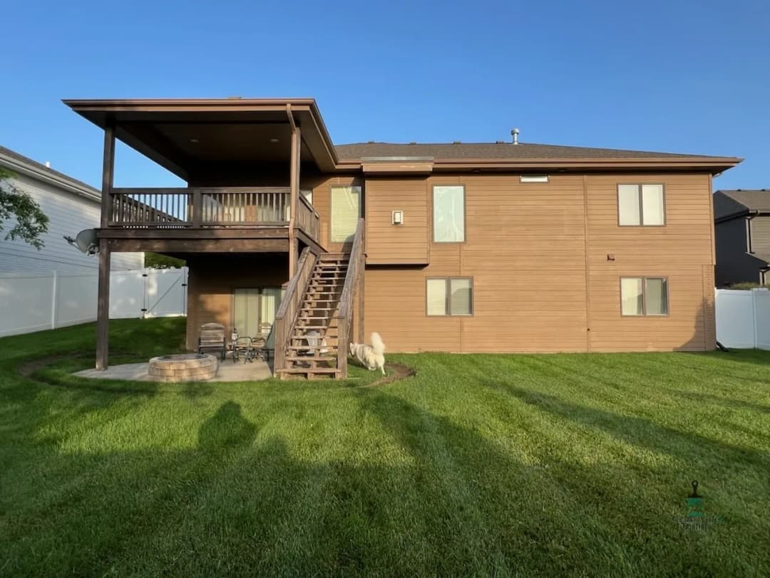 Modern two-story house with a backyard, deck, and green lawn features.