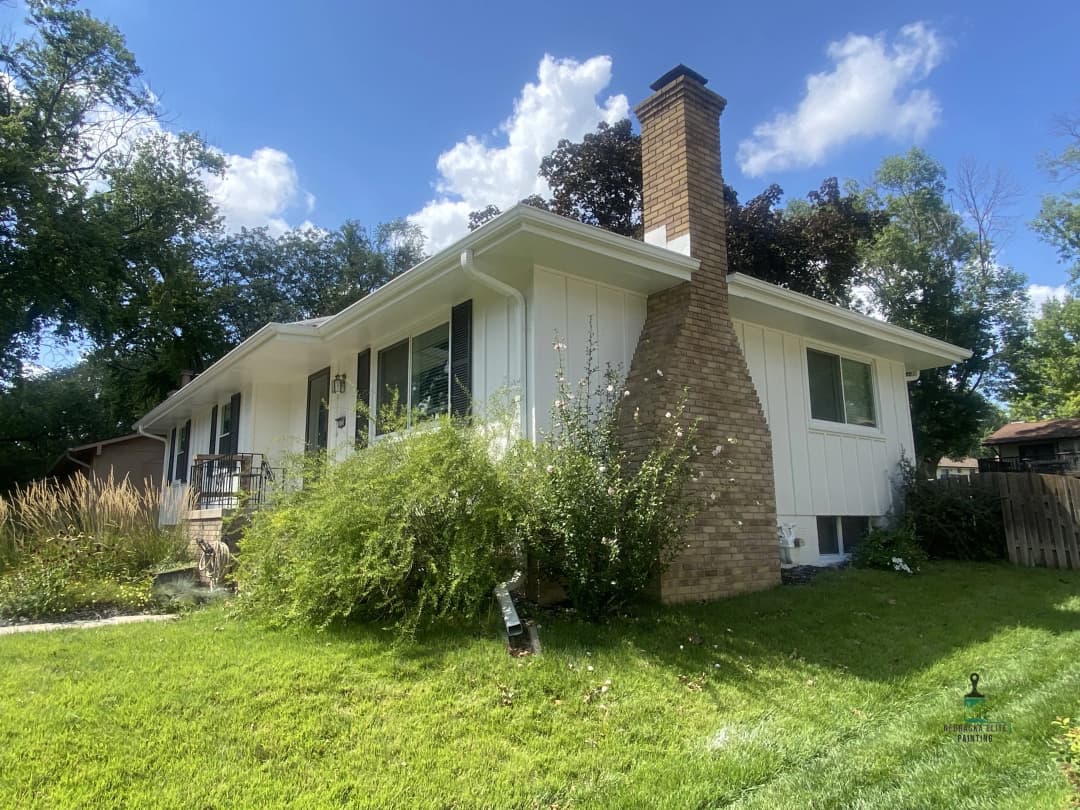 Single-story home with a chimney, lush front yard, and blue sky backdrop. Ideal for families.