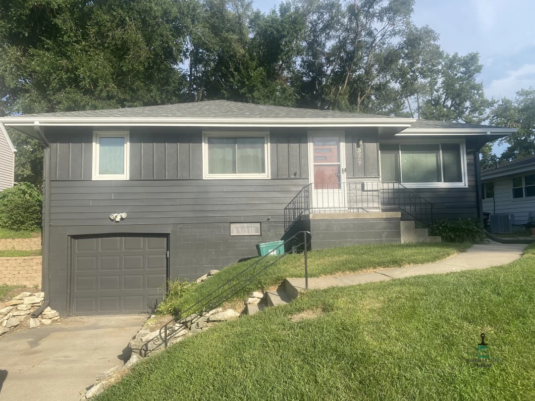 Modern gray single-family home with garage and front steps, surrounded by green lawn.