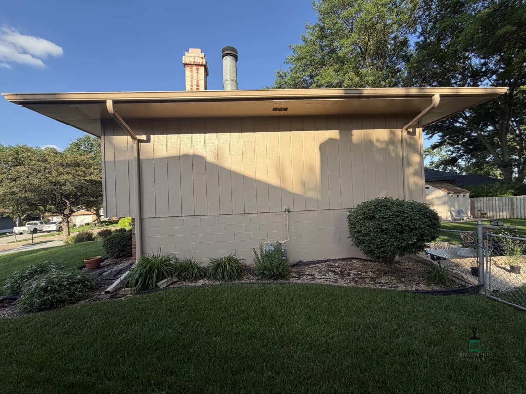 Side view of a modern home exterior with green landscaping and chimney.
