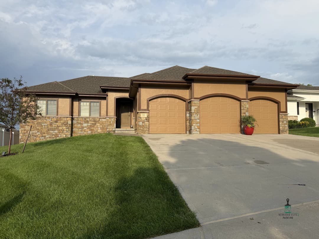 Modern single-family home with stone accents, three garage doors, and well-maintained lawn.