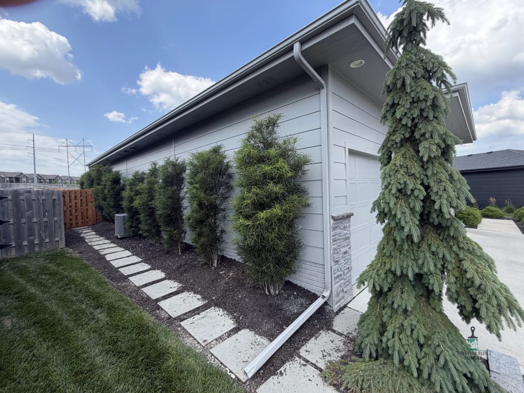 Side view of a modern home with manicured shrubs and a rock pathway.