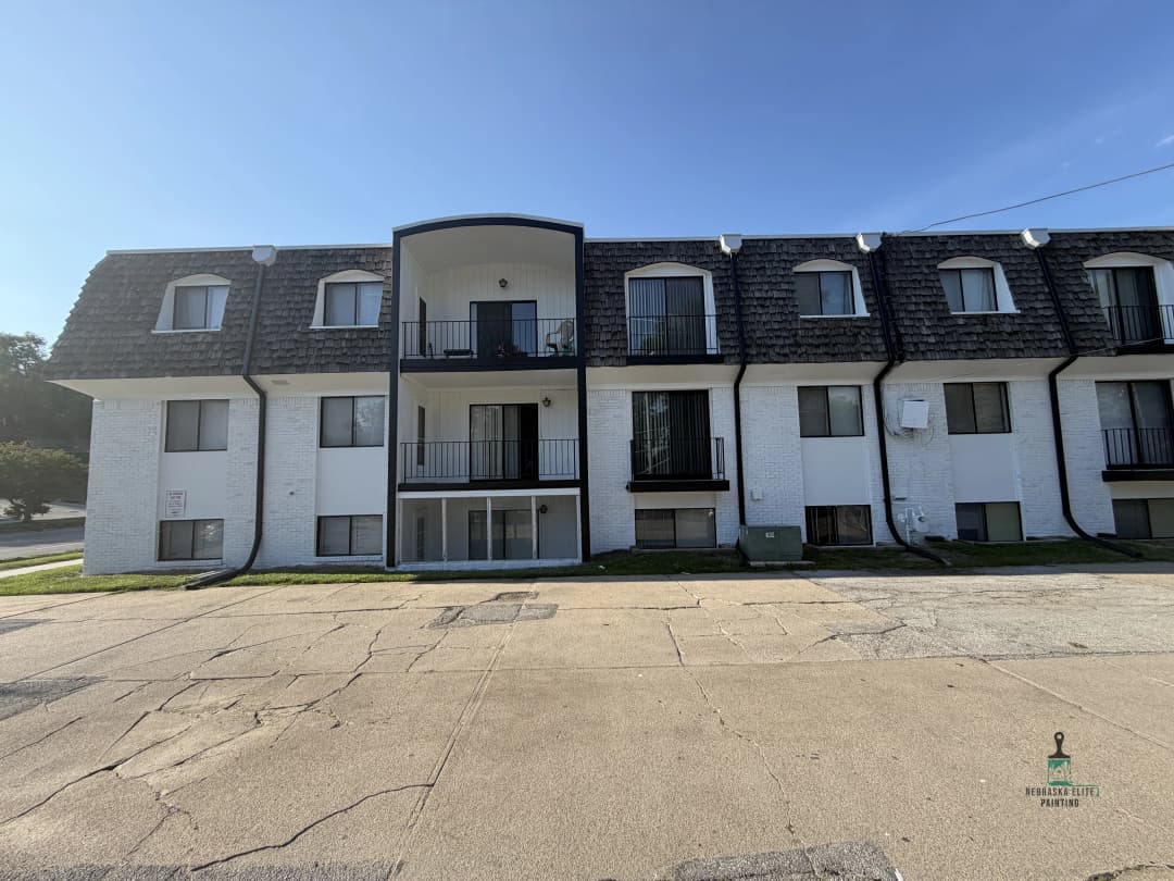 Modern two-story apartment building with balconies and a unique roof design, located in a sunny area.