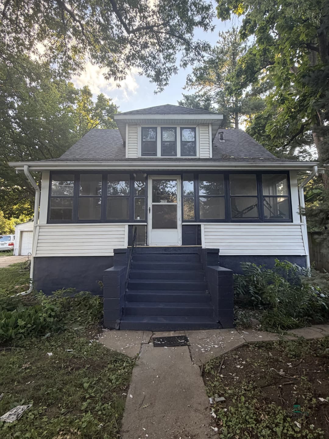Victorian-style home with a blue and white facade, large front porch, and landscaped yard.