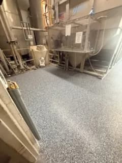Industrial hallway with new textured flooring and machinery in the background.