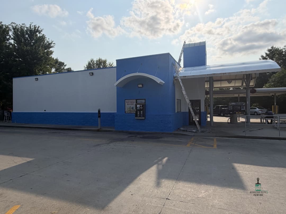 Blue and white drive-thru building with ladder and clear sky in the background.