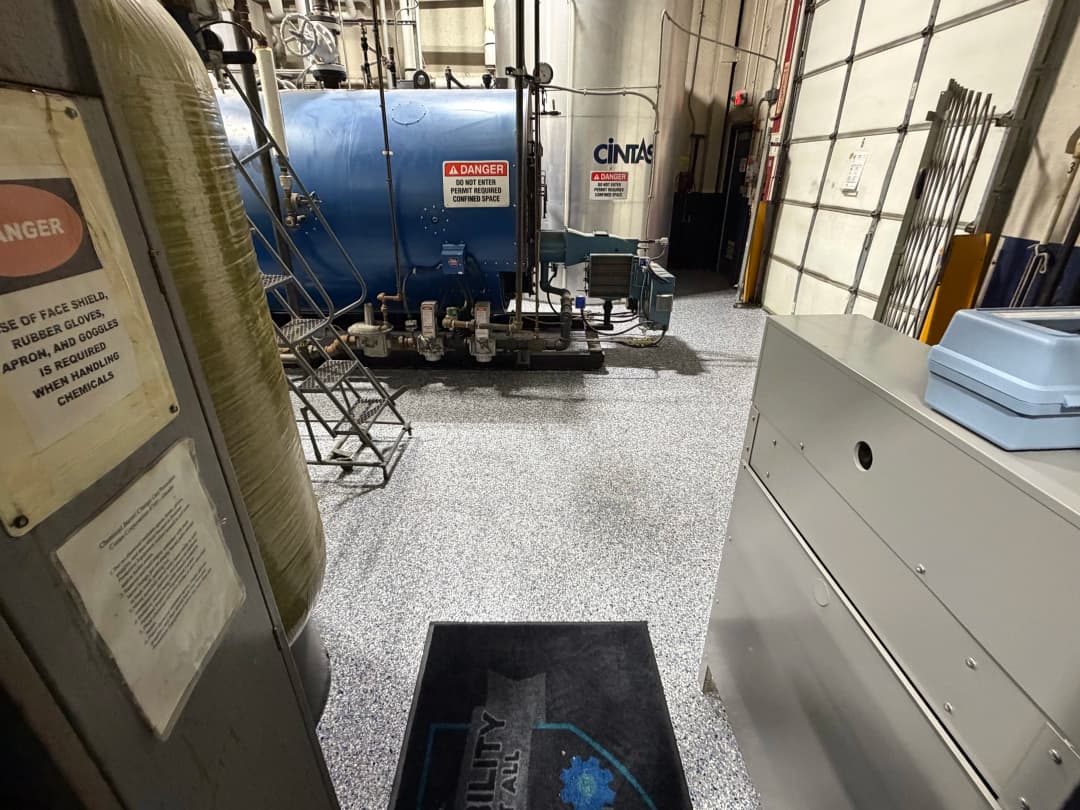 Industrial interior featuring a blue boiler, safety signage, and textured flooring.