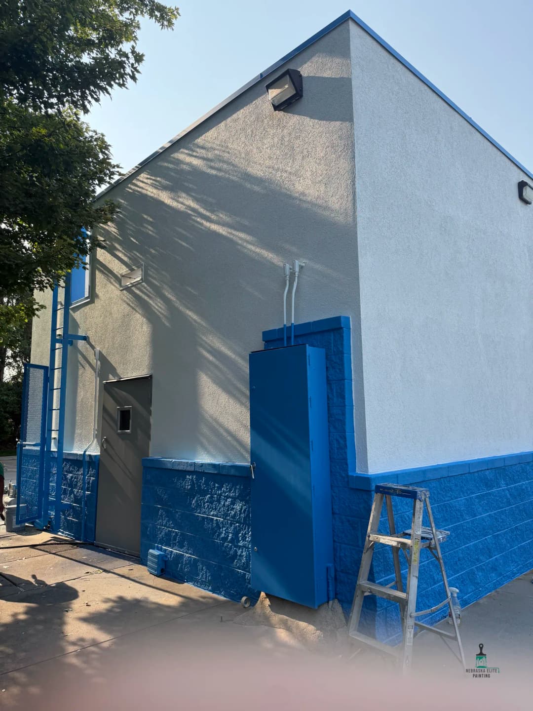 Freshly painted commercial building with blue accents and a ladder nearby.