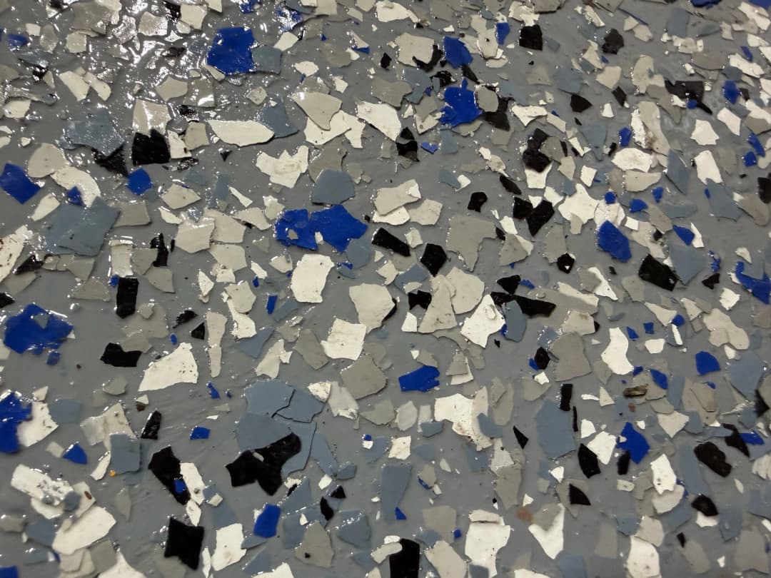 Close-up of a decorative epoxy floor with blue, white, gray, and black chips.