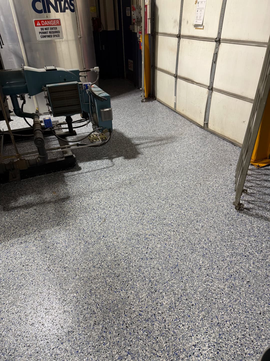 Industrial floor with blue-speckled epoxy finish in a warehouse setting.