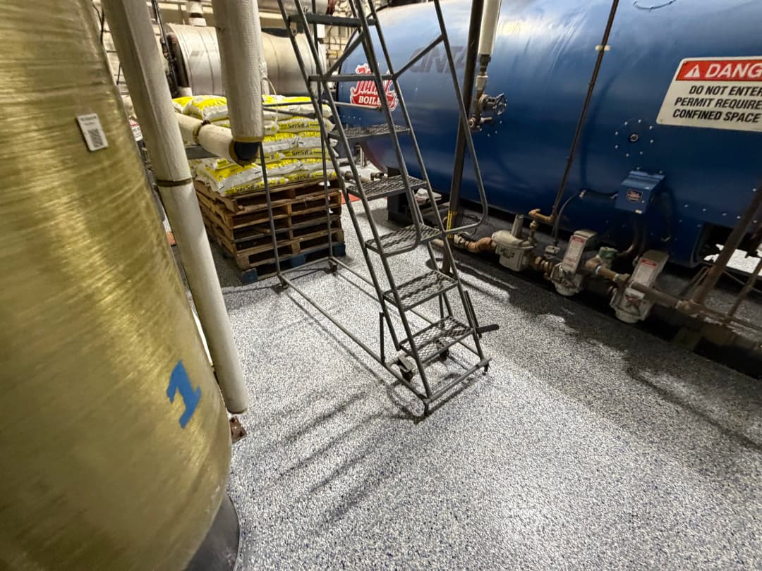 Industrial facility interior featuring storage tanks, safety signage, and equipment.