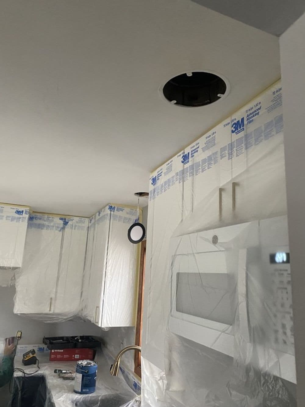 Kitchen renovation in progress with ceiling fixture removed and protective covering in place.