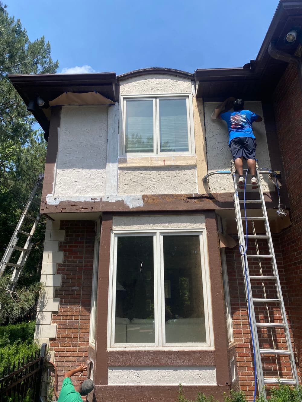 Home exterior renovations with workers on ladders applying new siding.