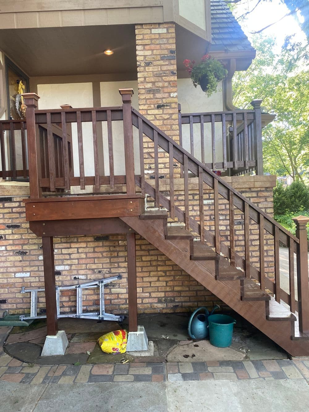 Wooden staircase leading to a brick house with potted plants and outdoor decor.