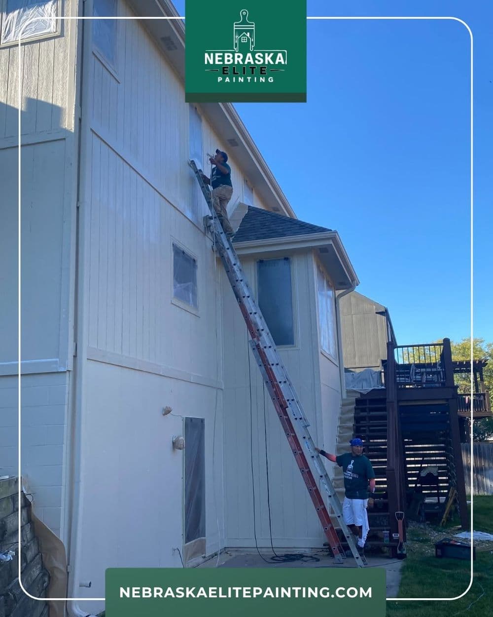 Professional painters using a ladder to paint a residential exterior wall. Nebraska Elite Painting.
